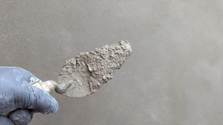 Trowel of breathable render being worked onto a wall, the repair that keeps wind-driven rain out of Carlisle masonry