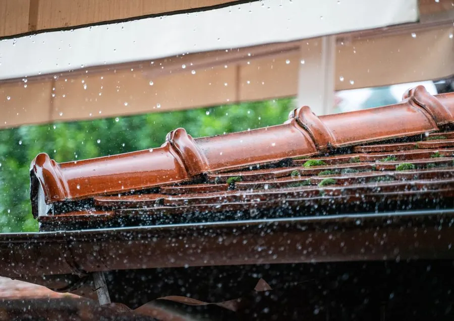 Rain running off a pitched tiled roof into the gutter, the drainage advantage a converted extension roof gains in Carlisle