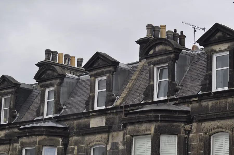 Slate rooflines and dormers running along a street of older houses, the ridge line sitting along the top of each roof