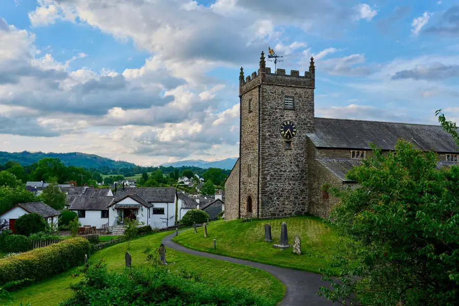 Slate roofs and long ridge lines on a stone church and village houses in Cumbria, the kind of ridge work priced for Carlisle homes