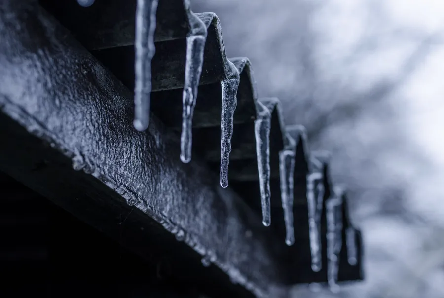 Icicles hanging from the edge of a roof, a sign meltwater is stopping at the gutter rather than draining