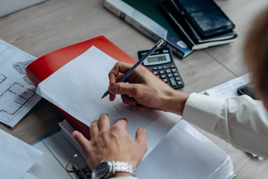 Roofing quote paperwork, drawings and a calculator laid out while comparing re-roof prices in Carlisle