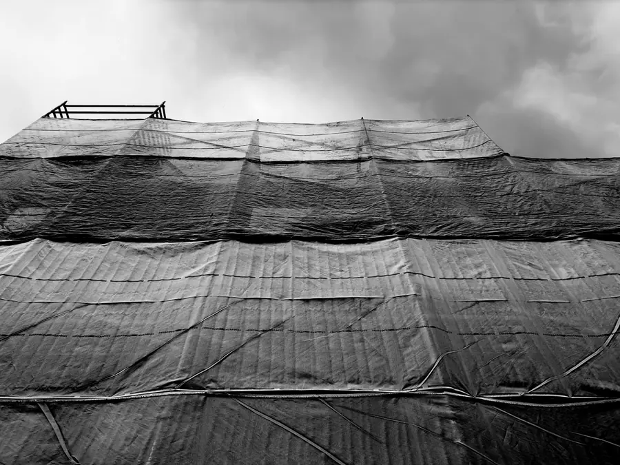 Scaffolding sheeted over for a roof strip, the kind of enclosed access needed on the tight shared frontages of Penrith's town-centre yards