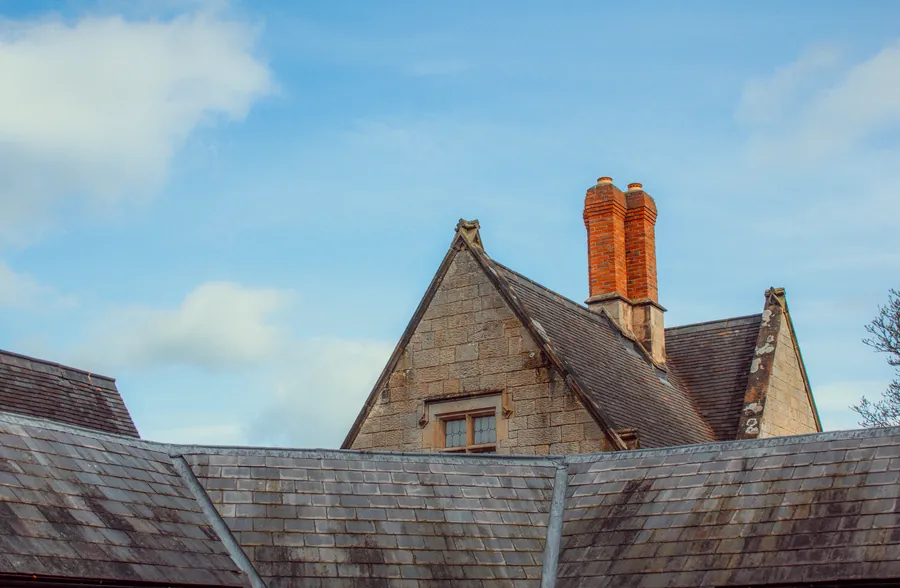 A British slate roof with stone gable and clay chimney pots, the kind of covering solar brackets have to be fixed through in Carlisle