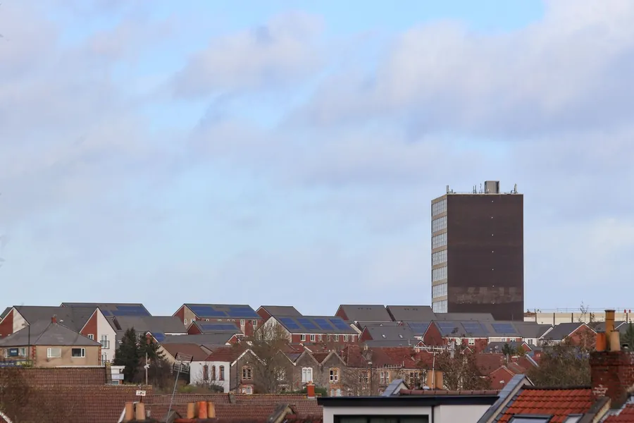 Solar panels on rows of British house roofs with chimney pots in the foreground, showing the typical northern England installation Carlisle homeowners are quoted for