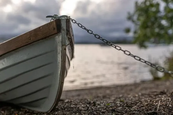 A wooden rowing boat chained at the water's edge, the timeless furniture of Bowness Bay