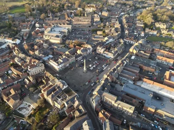 Aerial view of a market town centre with a memorial monument at its heart, as at Wigton's market place