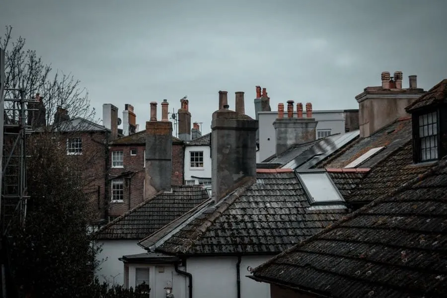 Chimney pots and flaunching seen across a row of British rooftops, the detail that fails first on a Carlisle stack