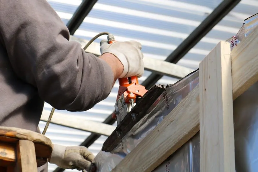A fitter working gloved on a roof detail, the stage where a roof window is made watertight