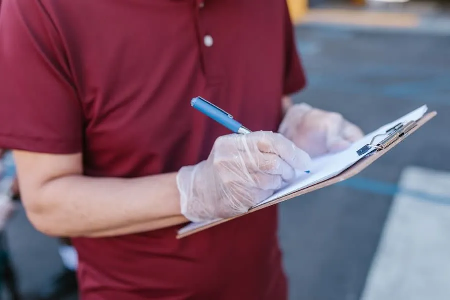 A surveyor working through an inspection checklist on a clipboard outside a property