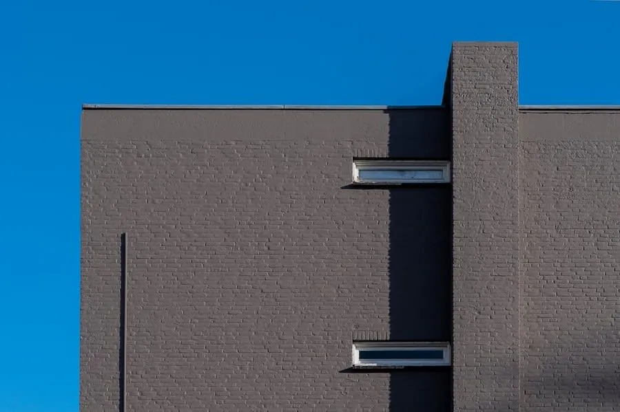 Flat-roofed brick building with a parapet edge seen against a clear sky