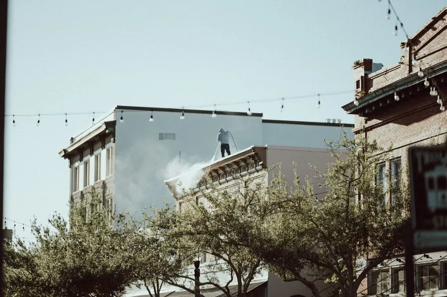 High pressure washing being used on a building exterior, a technique that damages roof coverings in Carlisle