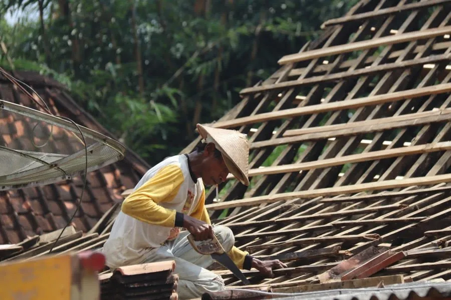 A carpenter working on a wooden roof structure, renewing timbers after decay has been cut out