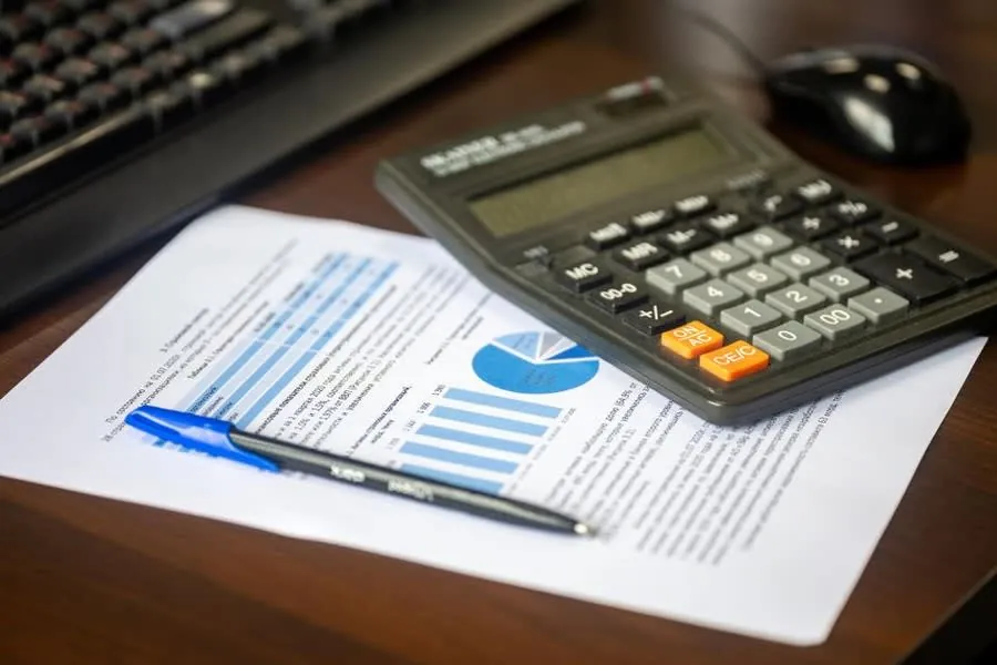 Calculator and printed roofing quote on a desk, working out what a roof repair in Carlisle will cost