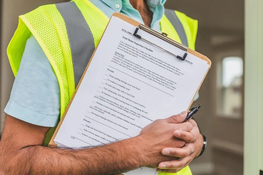 A surveyor with a clipboard and checklist assessing a property's condition