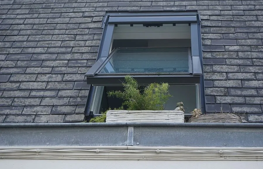 An open roof window fitted into a grey slate roof slope, the covering on most of Carlisle's older terraces