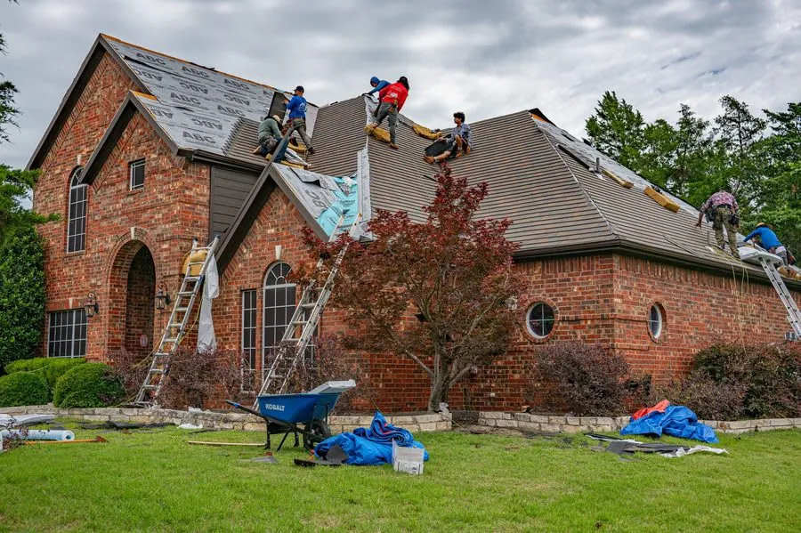 Roofers working from ladders on a pitched roof carrying out moss removal in Carlisle