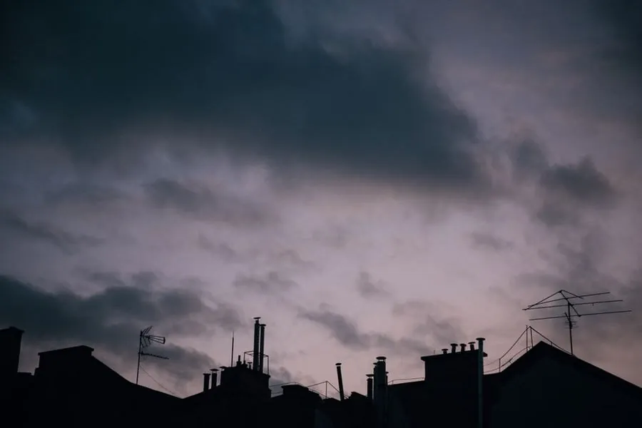 Storm clouds gathering over chimneys and rooftops, the weather that dislodges slates in Carlisle