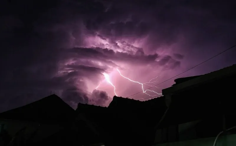 Lightning over houses during a severe storm of the kind that damages roofs across Cumbria